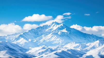 Obraz premium Snowy Mountain Peak Under Bright Blue Sky with Fluffy Clouds