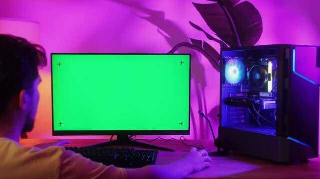 Computer with chroma key green screen on monitor. Gamer man playing in popular video games. Programmer or hacker coding a code and working in networks, cyberspace. Digital software, mobile app