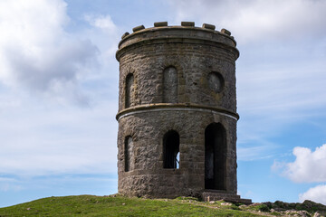 Grin Low Buxton , England - APRIL 18, 2022: with a pointed roof sits on a hill. The building is empty and has no windows. The sky is cloudy and the grass is green