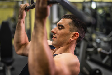 young muscular man do exercise for chest on the exercise cable machine