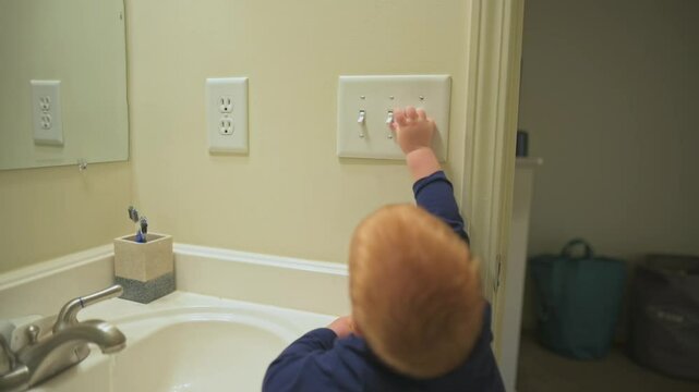 Toddler Reaching for Light Switch in Bathroom young child stretching to reach light switch in bathroom, exploring independence and curiosity in safe home environment Toddler safe home