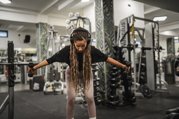 young woman with dumbbells flexing muscles in gym