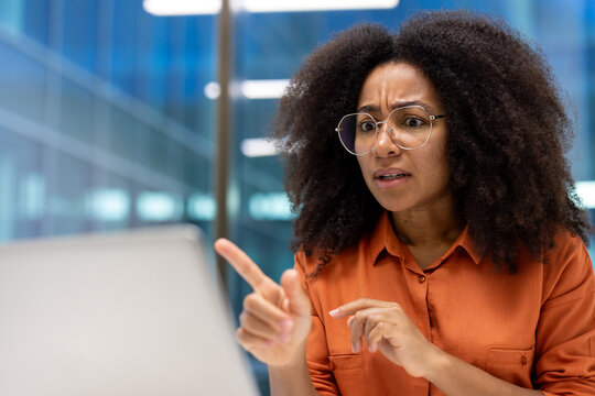 Anxious woman talking to colleagues using video call, office worker inside office closely communicating and discussing with subordinates. Businesswoman coordinating work of enterprise.