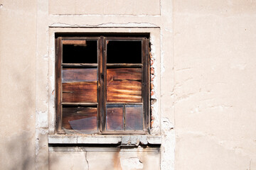 Old wooden window with broken glass on the wall of an abandoned house