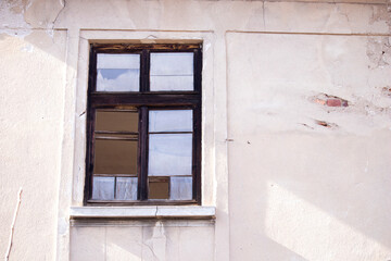 Fototapeta premium Old wooden window with broken glass on the wall of an abandoned house