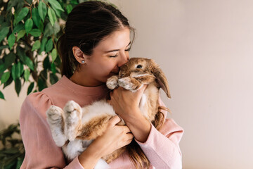 Young woman kissing her lovely pet rabbit at home