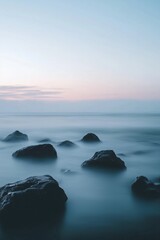 Obraz premium Tranquil seaside rocks at dusk with soft pastel horizon sky