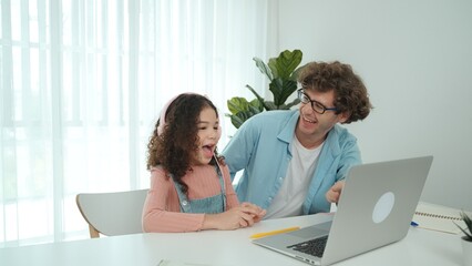 Caucasian dad put headphones on daughter while girl learning code. Father take care schoolgirl...