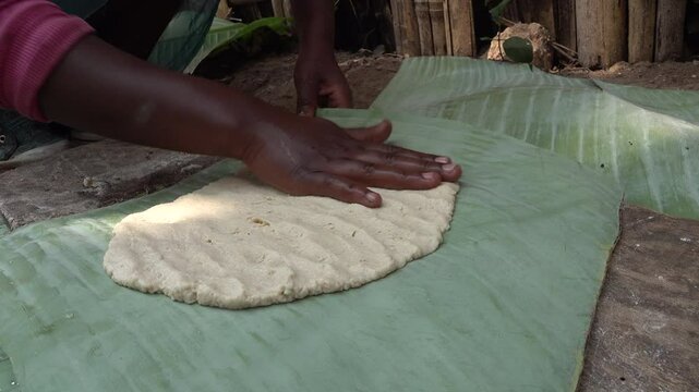 Close-up of hands of woman preparing fresh bread made from fermented banana leaves in rural tribal village of Dorze in Ethiopia

