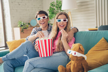 Young couple enjoying a fun movie night at home with 3D glasses and popcorn