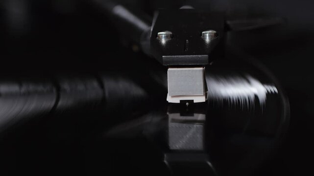 Retro Vinyl record player playing music, close-up macro shot of vintage LP disc old phonograph spinning. Retro music player at home.