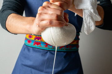 Chef squeezing almond milk through cloth strainer, preparing vegan milk