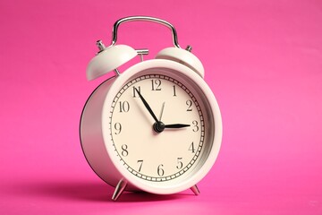 One white alarm clock on bright pink background