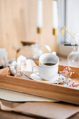 espresso coffee in a white cup on a white saucer on a wooden tray under the sun's rays, a transparent teapot with coffee, flowers, a book, morning coffee, drink, light composition, still life