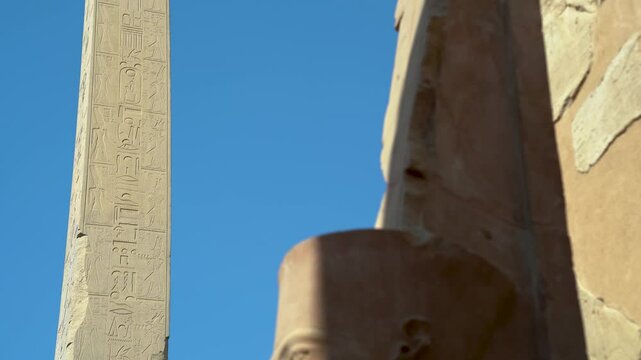 View of a tall obelisk in the ancient city of Karnax with an Egyptian statue of a pharaoh