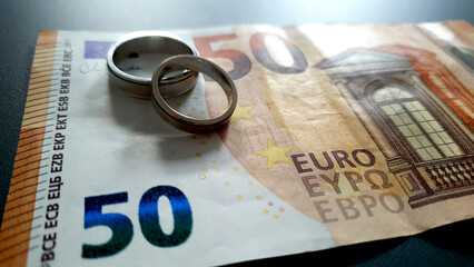 Wedding rings lying next to Euro banknote. Marital property. Divorce