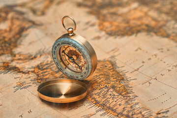 Antique brass compass resting on a world map, symbolizing travel and adventure.