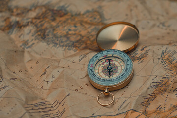 Antique brass compass resting on a world map, symbolizing travel and adventure. © vadish