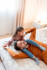 Father and Daughter Laughing and Playing on the Bed. Happy father and daughter share a joyful...