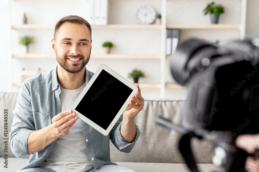Poster positive male vlogger recording video review of tablet computer at home, mockup. happy blogger showi