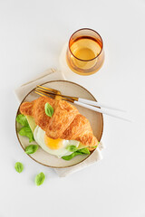Croissant toast with lettuce, cheese and fried egg on white table. Top view