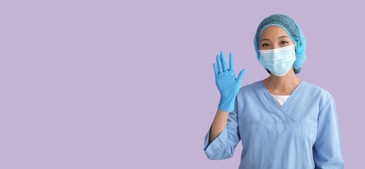 Asian nurse waving hand on lilac background with space for text