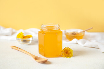 Jar and bowls with dandelion honey on white table
