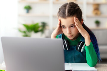 Bored Young Female Pupil Sitting At Desk With Laptop Computer At Home, Tired Upset Adolescent...