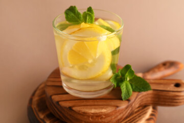 Glass of infused water with lemon and mint on brown background