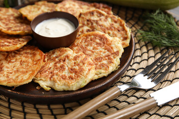 Plate of tasty zucchini fritters with sour cream on table