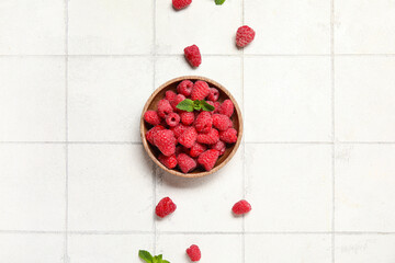 Bowl with fresh raspberry and mint on light tile background