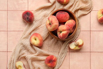 Wooden bowl with sweet fig peaches on pink tile background