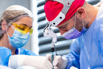 Surgeons work in sterile settings. Two healthcare workers focus intently while conducting a...