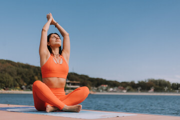 beautiful young woman does yoga on a city lake