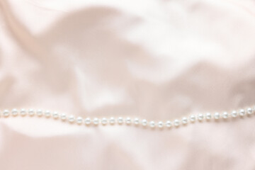 Beautiful pearl necklace on beige cloth, top view. Space for text