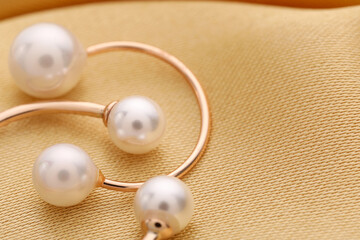 Beautiful pearl jewelry on golden silk, macro view. Space for text