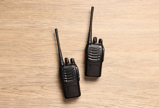 Walkie talkies on wooden table, top view