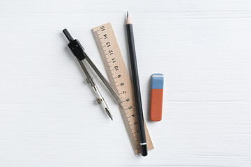 Naklejka premium Ruler, pencil, eraser and compass on white wooden table, flat lay
