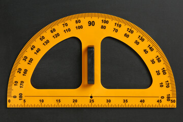 Protractor ruler on black chalkboard, top view