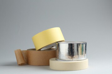 Rolls of different adhesive tapes on grey background