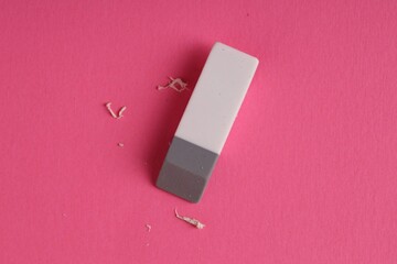 One eraser and scraps on pink background, top view