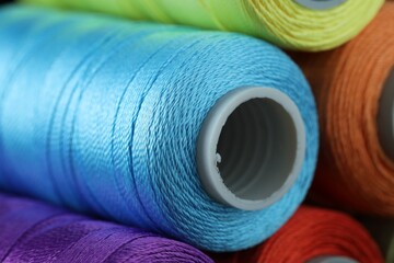 Spools of colorful sewing threads as background, closeup
