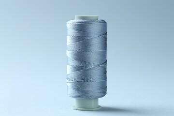 Spool of colorful sewing thread on light background