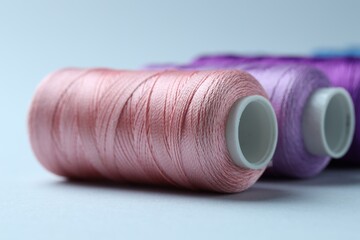 Spools of colorful sewing threads on light background, closeup