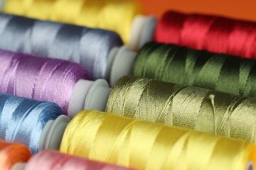 Different spools of sewing threads as background, closeup