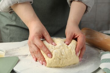 Woman kneading dough at table, closeup view
