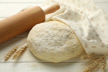 Fresh dough, rolling pin and spikes on white wooden table, closeup