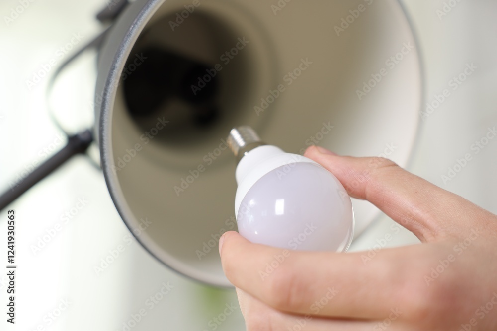 Wall mural Man changing light bulb in lamp at home, closeup