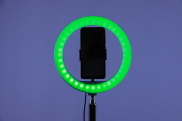 Ring lamp with smartphone on purple background