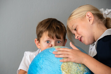Children Globe Education - Two young children looking at a globe in a studio setting, learning about the world.